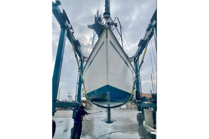 Slide: The Image of 1989 Hunter Vision 32 sailboat being cleaned with a pressure washer in a boatyard. - 64