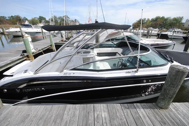 Slide: The Image of 2015 Formula 310 Bowrider docked at marina, featuring sleek black design and spacious seating. - 6