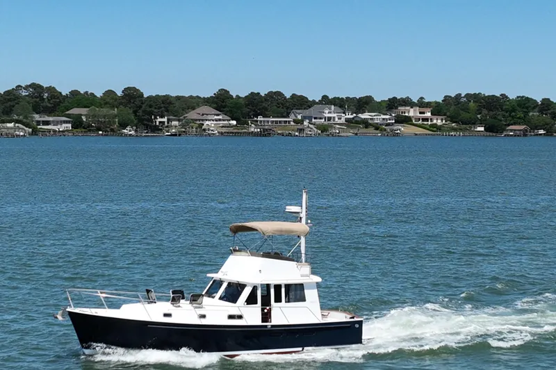 Slide: The Image of 1999 Legacy Yachts 40 Sedan cruising on a serene lake with waterfront homes in the background. - 106