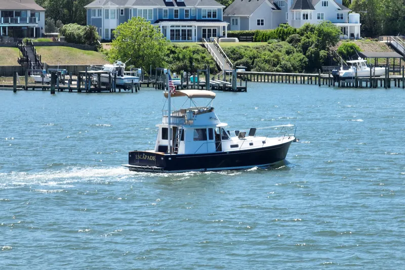 Slide: The Image of 1999 Legacy Yachts 40 Sedan cruising on a scenic waterfront with houses in the background. - 107