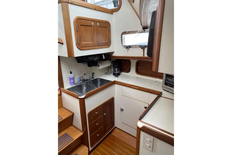Slide: The Image of 1999 Legacy Yachts 40 Sedan galley with wood accents, dual sink, and storage cabinets. - 16