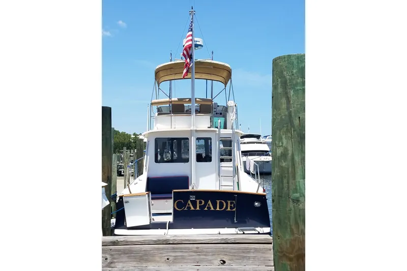 Slide: The Image of 1999 Legacy Yachts 40 Sedan docked, rear view with American flag, clear sky. - 37