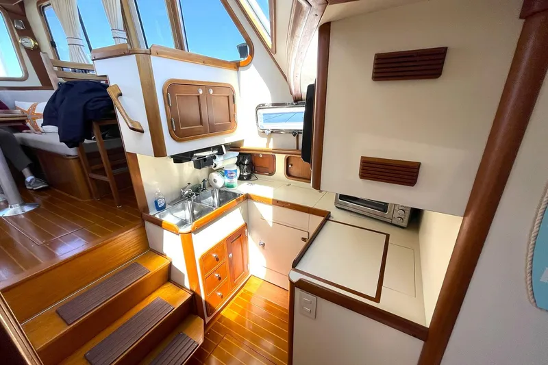 Slide: The Image of Interior of 1999 Legacy Yachts 40 Sedan, featuring compact kitchen and wooden accents. - 39