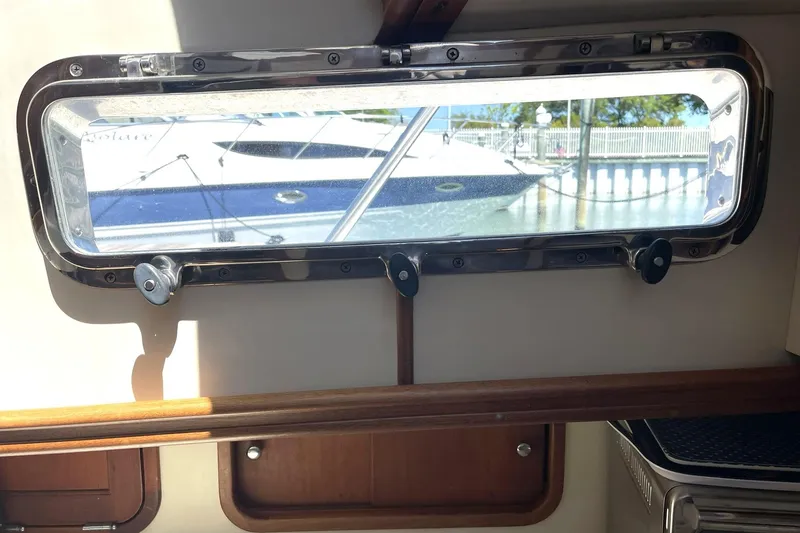 Slide: The Image of Porthole view from 1999 Legacy Yachts 40 Sedan, showcasing docked boats outside. - 42