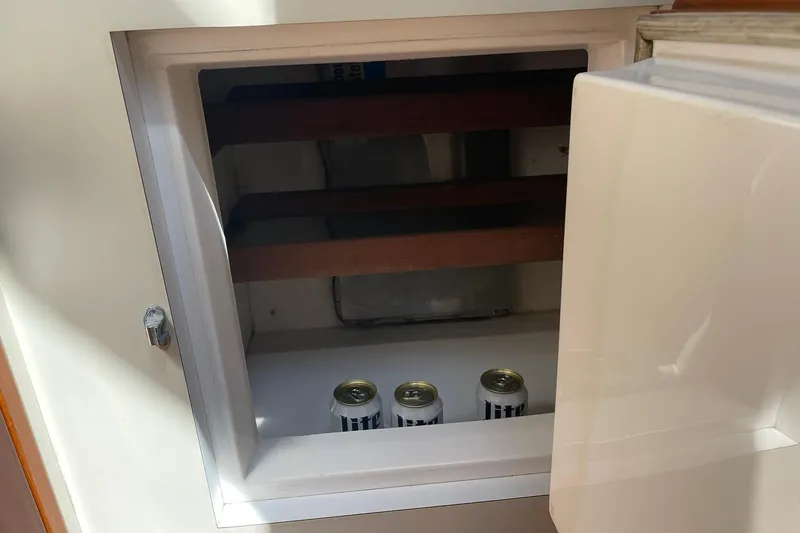 Slide: The Image of Small fridge with three cans inside on a 1999 Legacy Yachts 40 Sedan. - 44