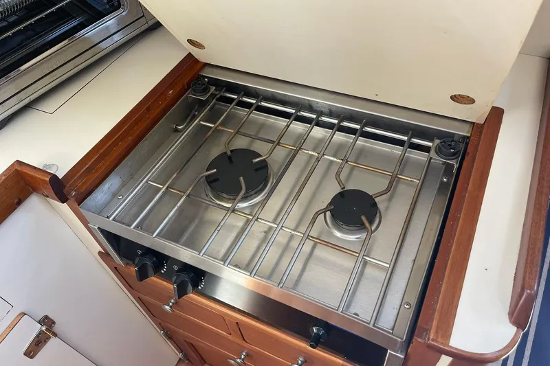 Slide: The Image of 1999 Legacy Yachts 40 Sedan kitchen with two-burner stove and wooden cabinetry. - 45