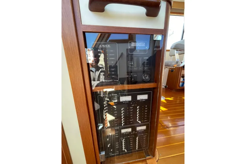 Slide: The Image of Electrical panel inside a 1999 Legacy Yachts 40 Sedan, featuring wooden trim and control switches. - 49