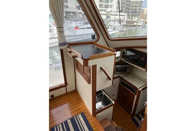 Slide: The Image of Interior of 1999 Legacy Yachts 40 Sedan, featuring a compact kitchen area with wood accents. - 6