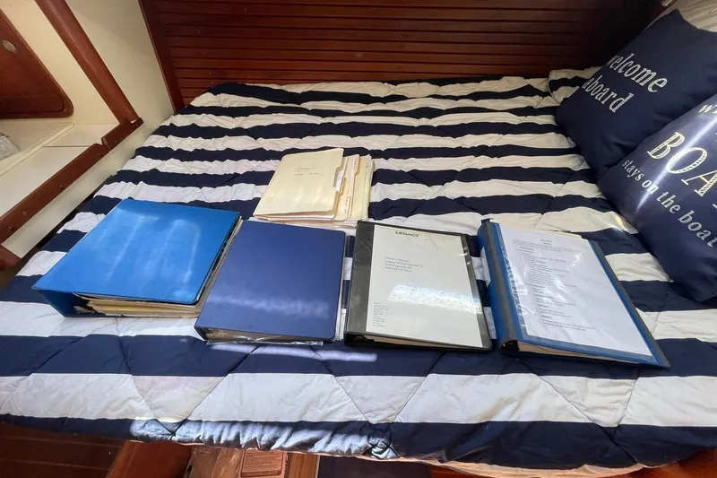 Slide: The Image of Binders and documents on a striped bed inside a 1999 Legacy Yachts 40 Sedan. - 75