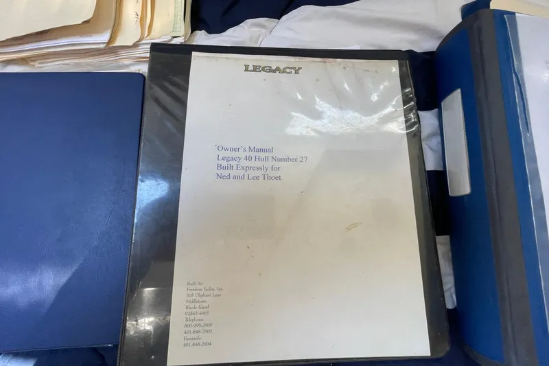 Slide: The Image of Owner's manual for 1999 Legacy Yachts 40 Sedan, Hull Number 27, on a table. - 76
