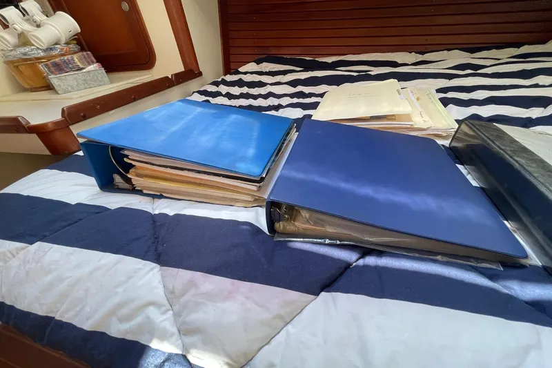 Slide: The Image of Binders with documents on a striped bed inside a 1999 Legacy Yachts 40 Sedan. - 78
