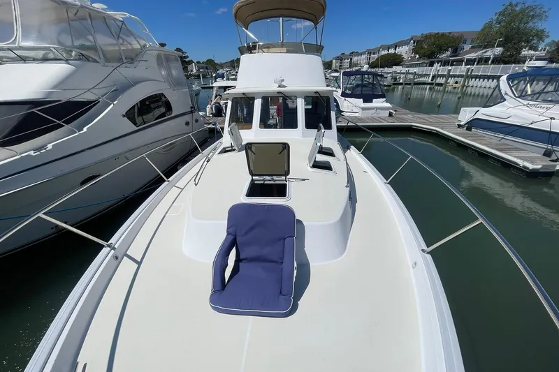 Slide: The Image of 1999 Legacy Yachts 40 Sedan docked, featuring spacious deck with blue cushion. - 81