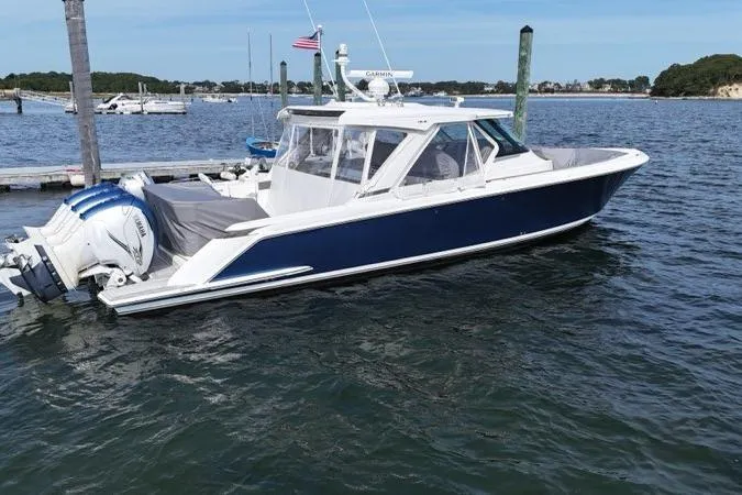 Slide: The Image of 2021 Tiara Sport 43 LS boat docked at a marina, featuring sleek design and blue hull. - 2