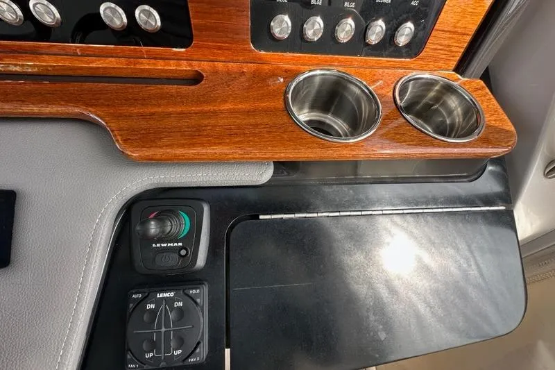Slide: The Image of 2021 Tiara Sport 43 LS dashboard with wood paneling, cup holders, and control switches. - 25