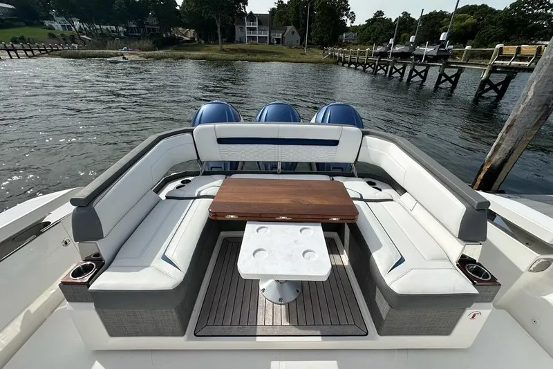 Slide: The Image of Luxury seating area on 2021 Tiara Sport 43 LS boat, docked by a scenic waterfront. - 45
