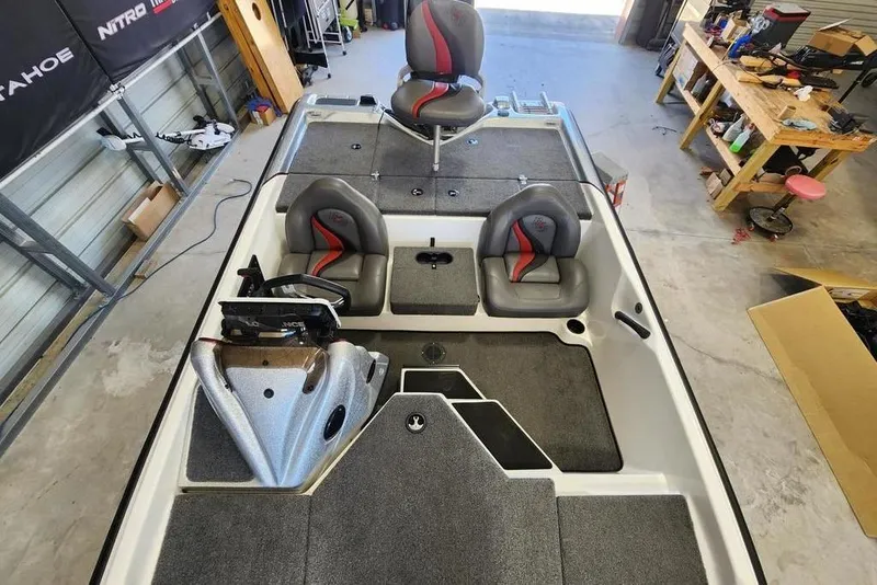 Slide: The Image of 2023 Bass Cat Bobcat boat interior with gray seating and carpeted deck in a garage. - 8