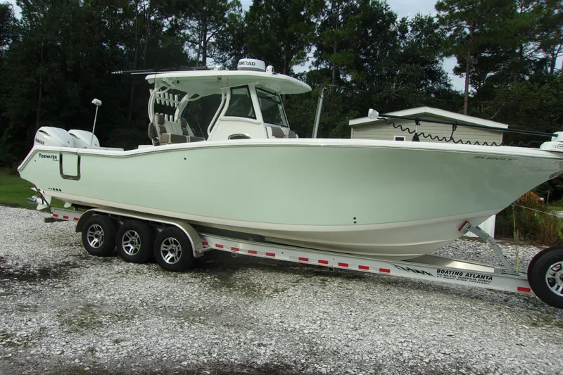 Slide: The Image of 2025 Tidewater 320 CC Adventure boat on trailer, parked outdoors. - 4