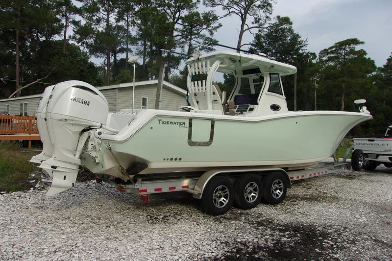 Slide: The Image of 2025 Tidewater 320 CC Adventure boat on trailer, parked outdoors near trees. - 47