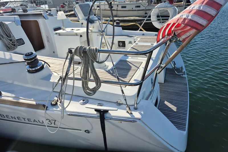 Slide: The Image of 2011 Beneteau Oceanis 37 sailboat docked, featuring deck and American flag. - 10