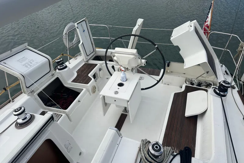 Slide: The Image of 2011 Beneteau Oceanis 37 cockpit with steering wheel, open storage, and wooden seating. - 16