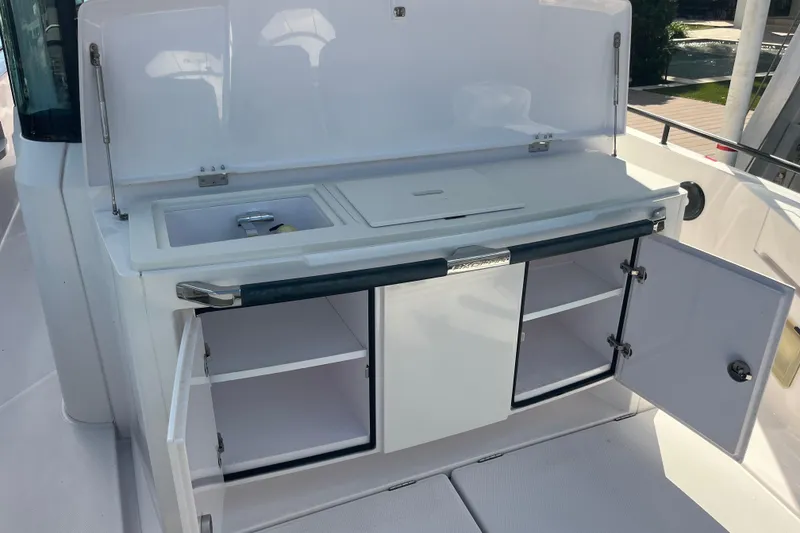 Slide: The Image of 2021 Axopar 37 Cross Cabin boat kitchen area with open storage and sink. - 18