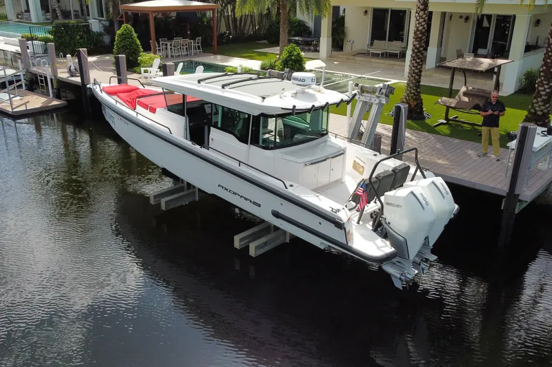 Slide: The Image of 2021 Axopar 37 Cross Cabin boat docked by a waterfront home. - 2