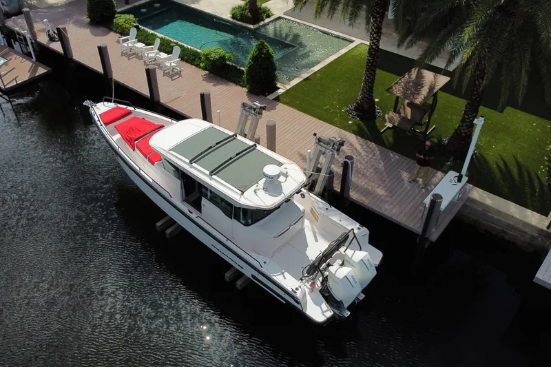 Slide: The Image of 2021 Axopar 37 Cross Cabin docked by a poolside with lush greenery. - 3