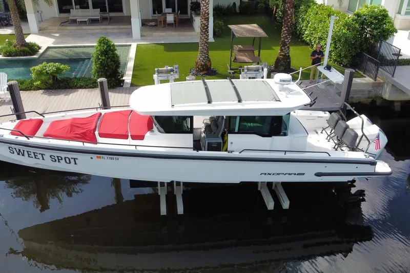 Slide: The Image of 2021 Axopar 37 Cross Cabin boat docked near a modern waterfront home. - 5