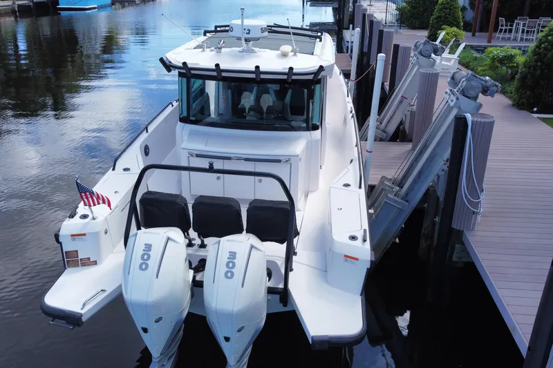 Slide: The Image of 2021 Axopar 37 Cross Cabin boat docked with dual engines and American flag. - 6