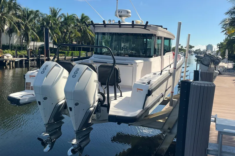 Slide: The Image of 2021 Axopar 37 Cross Cabin boat with dual Mercury engines docked by palm trees. - 8