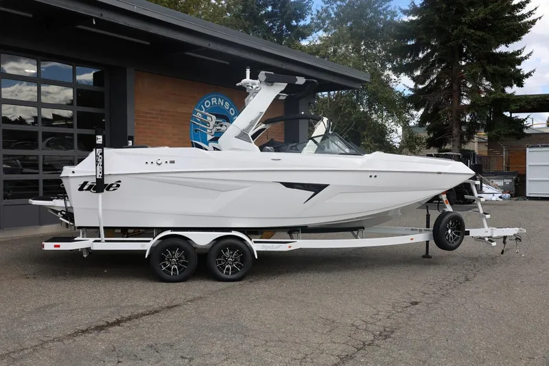 The Image of 2026 Tigé 22RZX boat on trailer, parked outdoors near a building. - 1