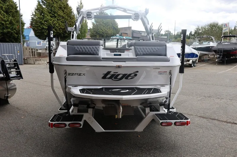 Slide: The Image of 2026 Tigé 22RZX boat rear view in a marina, showcasing sleek design and seating. - 11