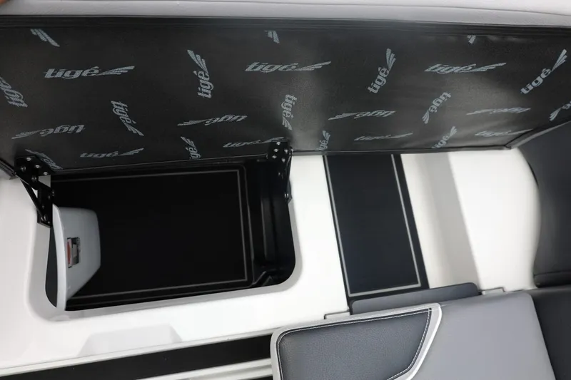 Slide: The Image of 2026 Tigé 22RZX boat interior storage compartment with branded lid. - 29