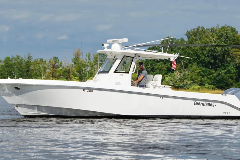 Slide: The Image of 2012 Everglades 325 Center Console boat cruising on a calm river with lush greenery. - 0