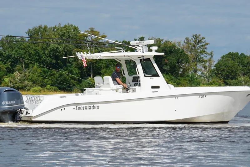 Slide: The Image of 2012 Everglades 325 Center Console boat cruising on a calm river with lush greenery. - 11