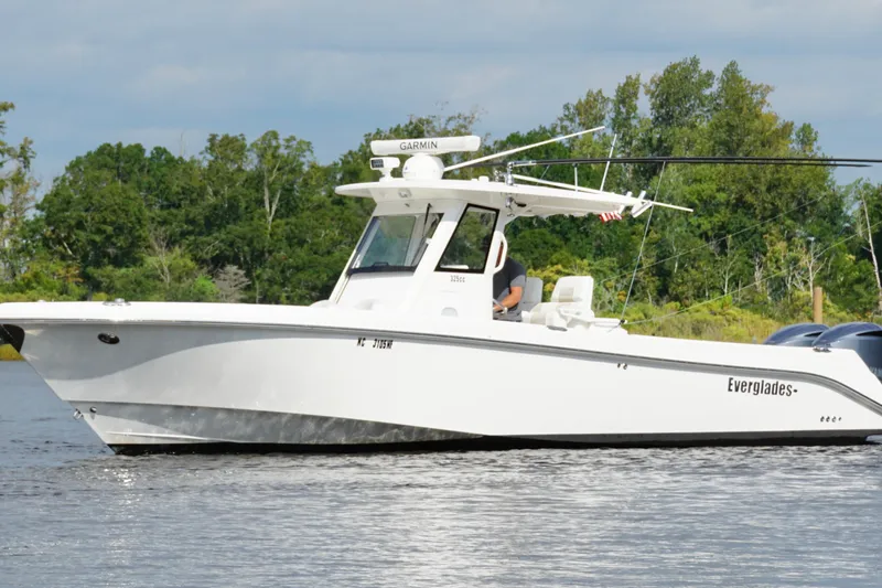 Slide: The Image of 2012 Everglades 325 Center Console boat on calm water, surrounded by lush greenery. - 13