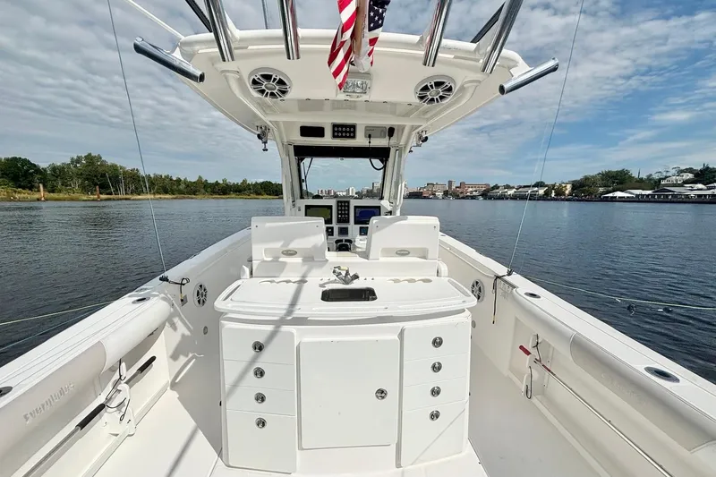 Slide: The Image of 2012 Everglades 325 Center Console boat on calm water, featuring a spacious deck and control panel. - 16