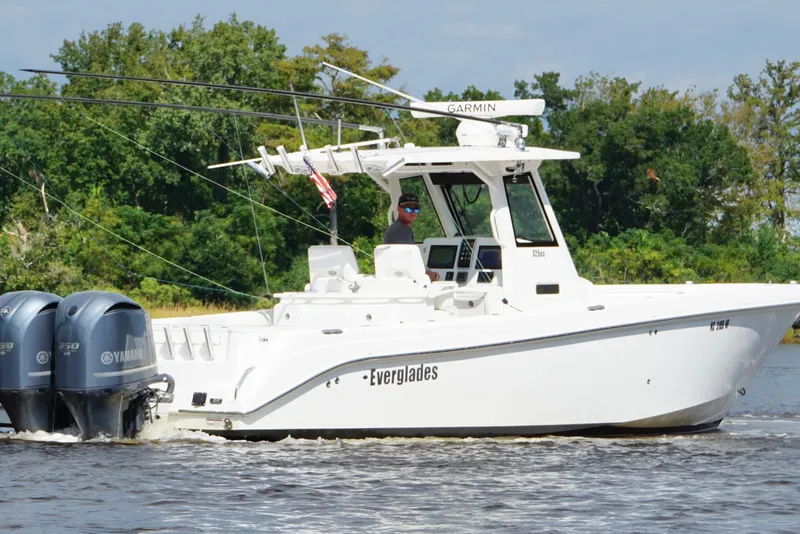 Slide: The Image of 2012 Everglades 325 Center Console boat cruising on a river with twin Yamaha engines. - 2