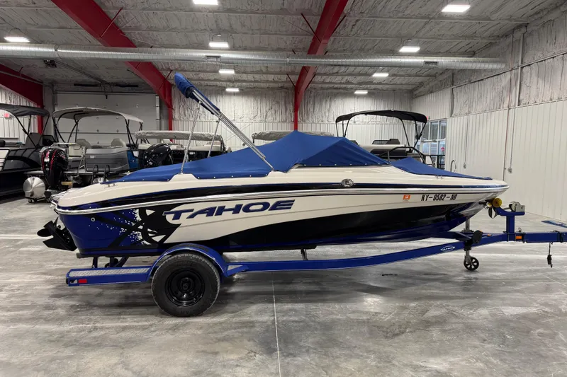 Slide: The Image of 2009 Tahoe Q5i boat with blue cover on trailer in indoor showroom. - 14