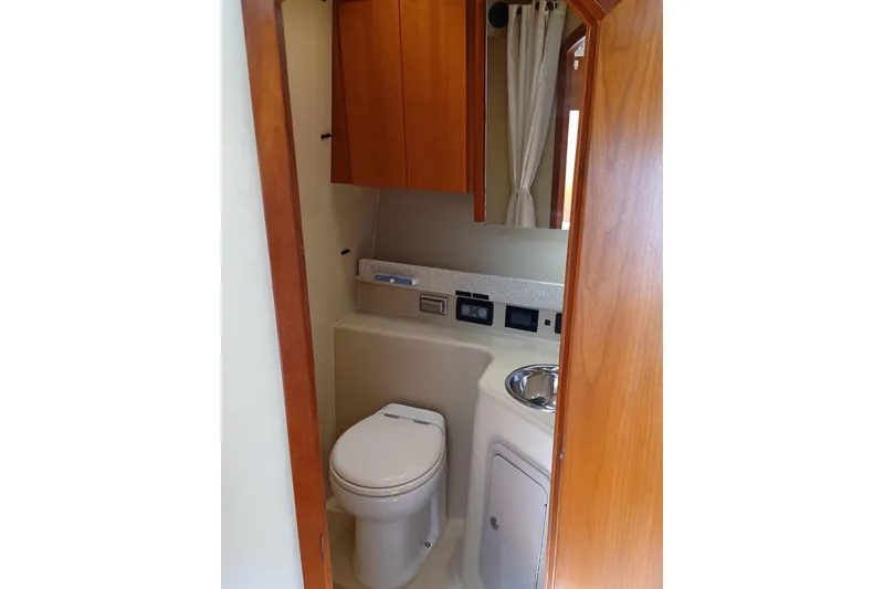 Slide: The Image of 2006 Rampage 33 Express boat bathroom with toilet, sink, and wooden cabinetry. - 12