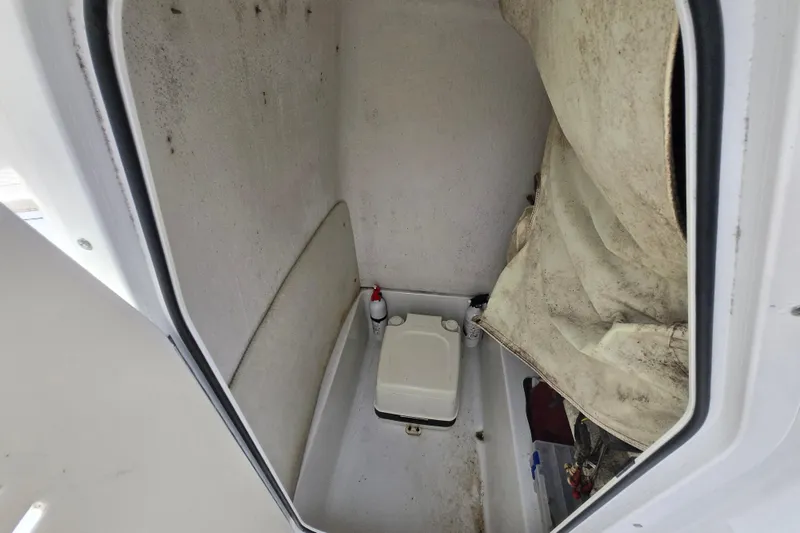 Slide: The Image of 2008 Sea Hunt Ultra 232 boat interior with white seating and helm, docked by water. - 13