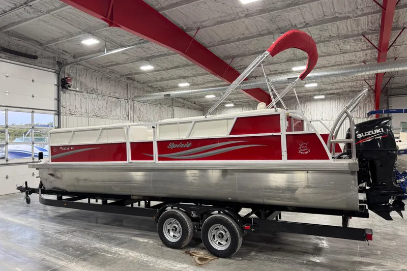 Slide: The Image of 2015 JC 241 Spirit TT Sport pontoon boat in a garage, featuring a Suzuki outboard motor. - 4
