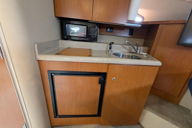 Slide: The Image of 2004 Cruisers Yachts 280 CXi Express kitchenette with sink, microwave, and mini-fridge. - 8
