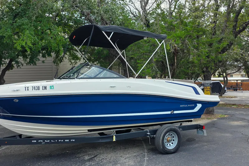 The Image of 2019 Bayliner VR4 Bowrider I/O boat on trailer, parked outdoors with trees in background. - 0