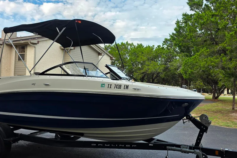 Slide: The Image of 2019 Bayliner VR4 Bowrider I/O boat on trailer, parked near trees and house. - 3