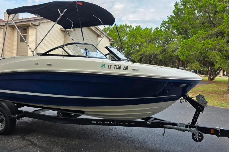 Slide: The Image of 2019 Bayliner VR4 Bowrider I/O on trailer, parked outdoors with trees in background. - 4