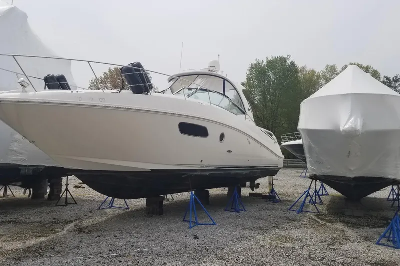 Slide: The Image of 2009 Sea Ray 350 Sundancer boat on stands, stored outdoors, with covered boats nearby. - 15