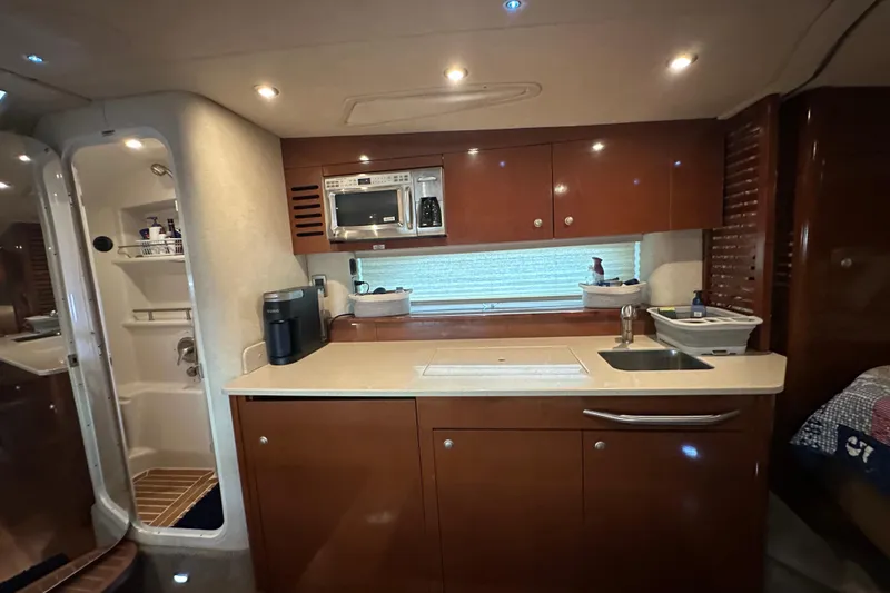 Slide: The Image of 2009 Sea Ray 350 Sundancer interior kitchen with wood cabinets, sink, and microwave. - 7