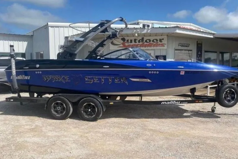 The Image of 2012 Malibu Wakesetter 22 MXZ boat on trailer, parked outside a dealership. - 1