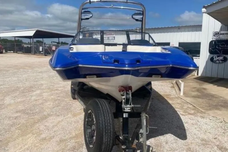 Slide: The Image of 2012 Malibu Wakesetter 22 MXZ boat on trailer, blue and white, parked outdoors. - 4